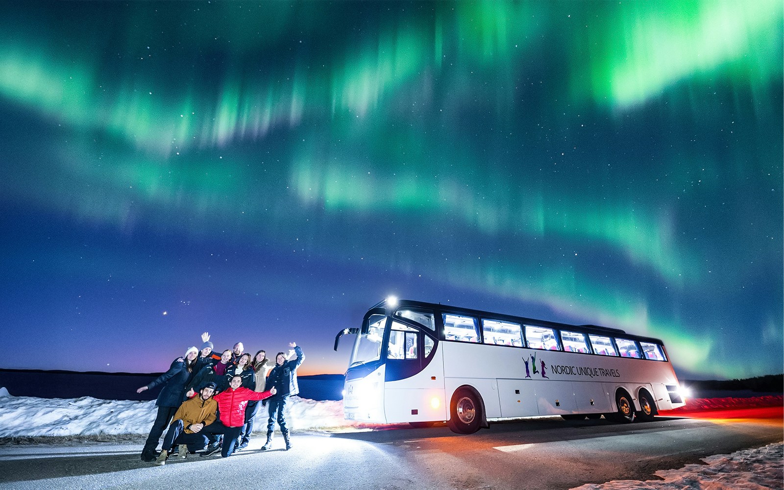 Guests on a bus tour watching Northern Lights in Rovaniemi.
