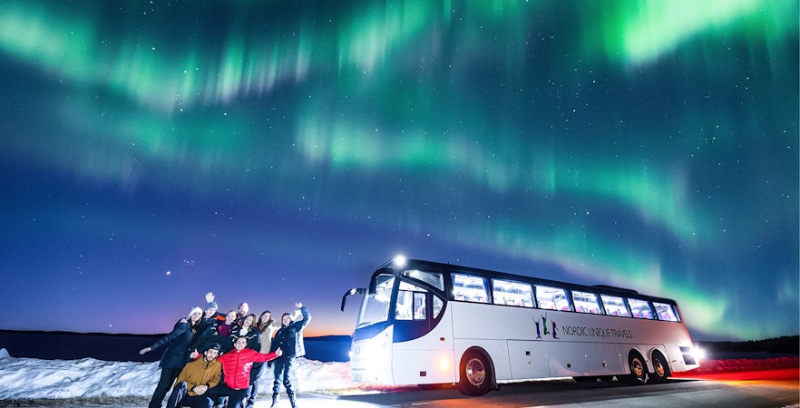 Guests on a bus tour watching Northern Lights in Rovaniemi.