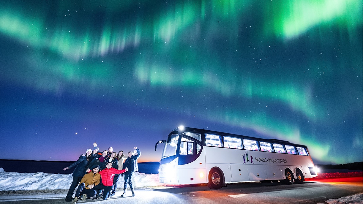 Guests on a bus tour watching Northern Lights in Rovaniemi.