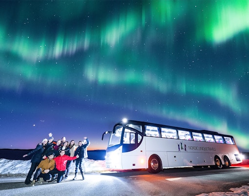 Guests on a bus tour watching Northern Lights in Rovaniemi.