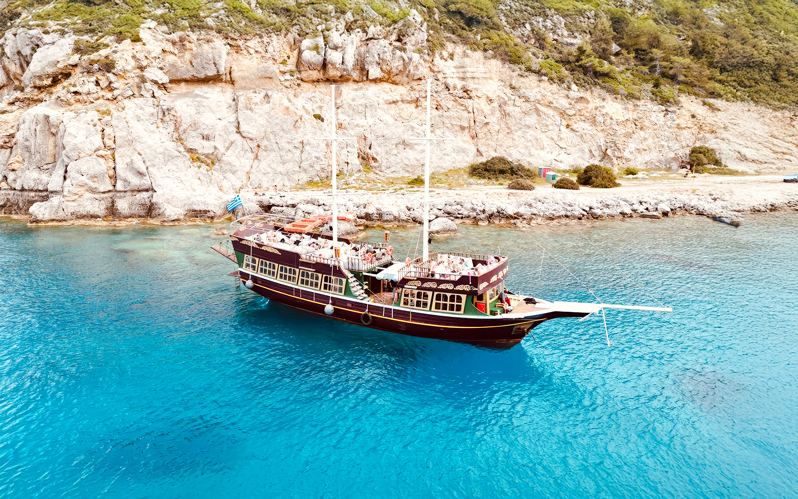 Sailing ship near rocky coast on daytime cruise, Rhodes.