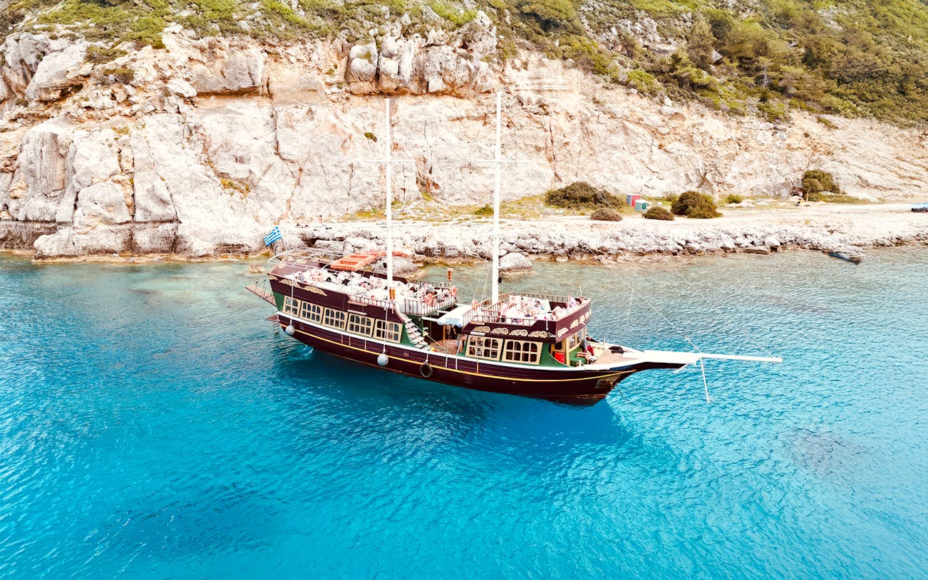 Sailing ship near rocky coast on daytime cruise, Rhodes.