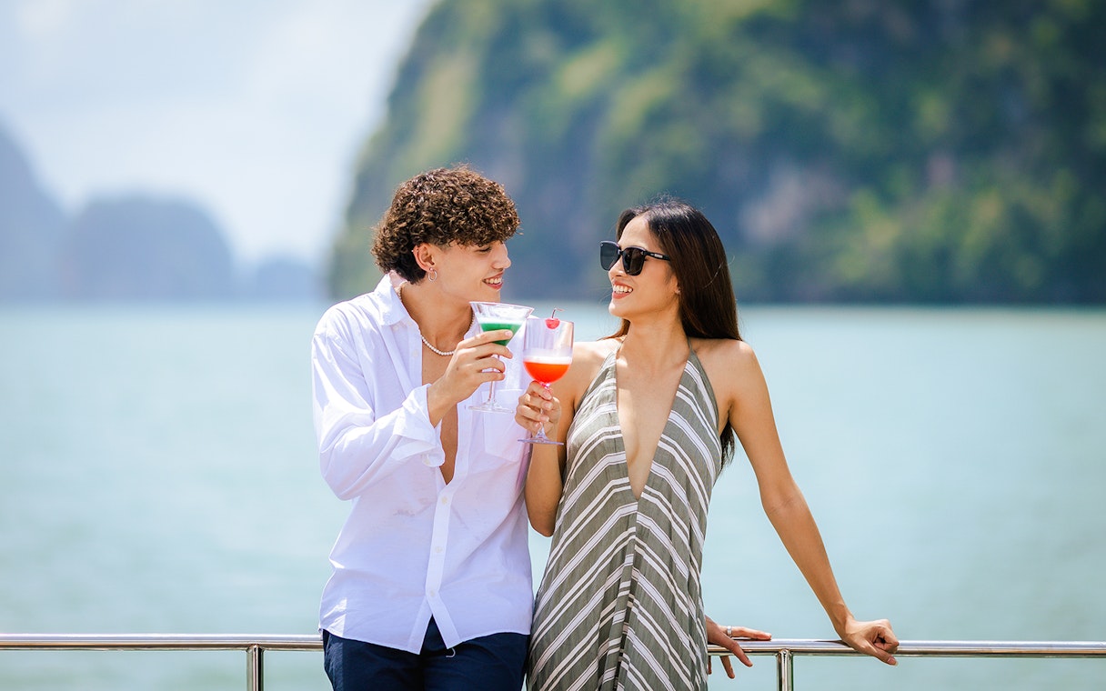 Couple enjoying welcome drinks on a boat with scenic ocean view.