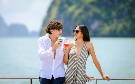 Couple enjoying welcome drinks on a boat with scenic ocean view.