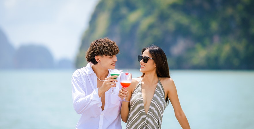 Couple enjoying welcome drinks on a boat with scenic ocean view.
