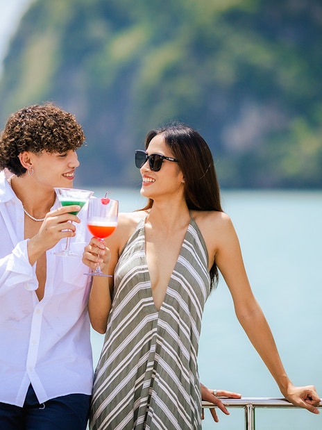 Couple enjoying welcome drinks on a boat with scenic ocean view.