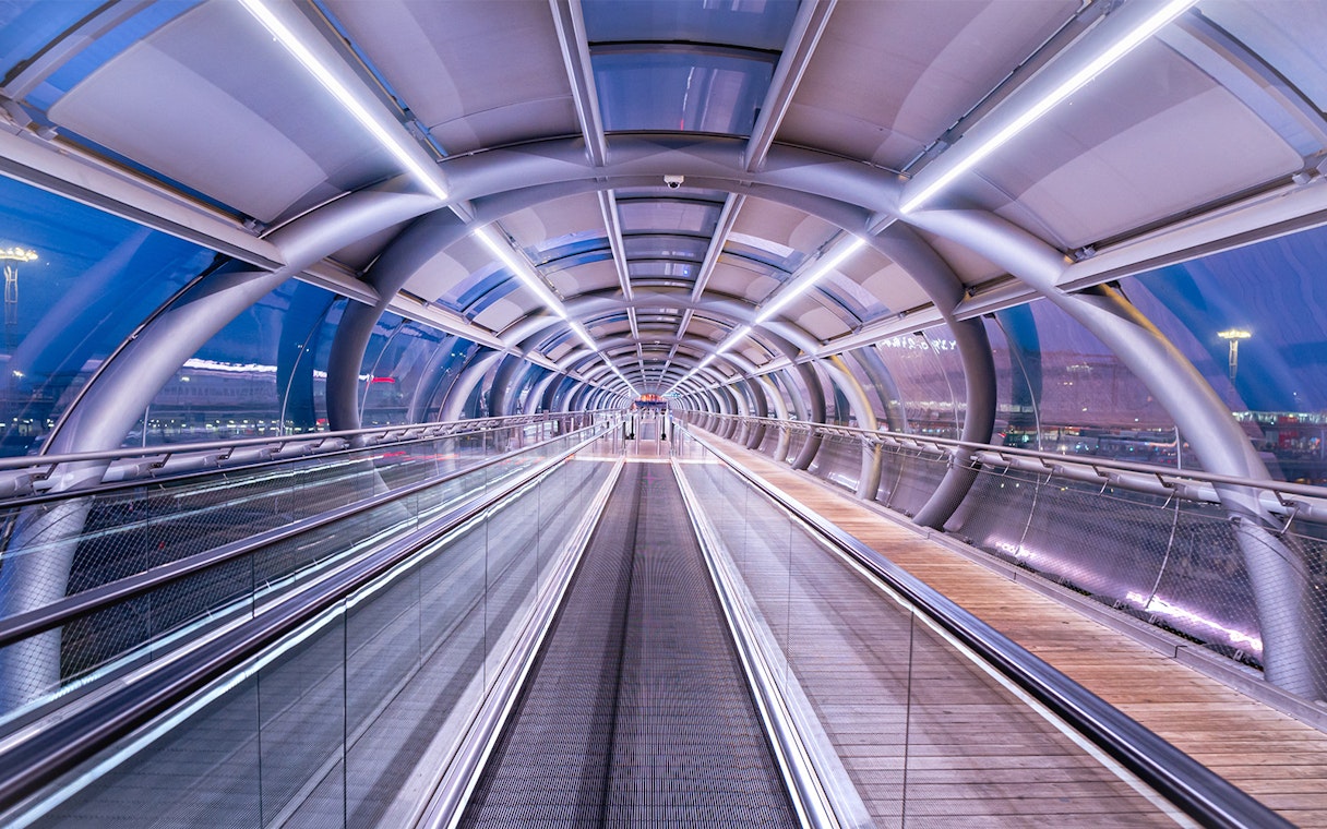 Futuristic walkway at Paris-Orly Airport with glass and metal design.