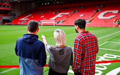Visitors observing Anfield Stadium field during Liverpool FC tour.