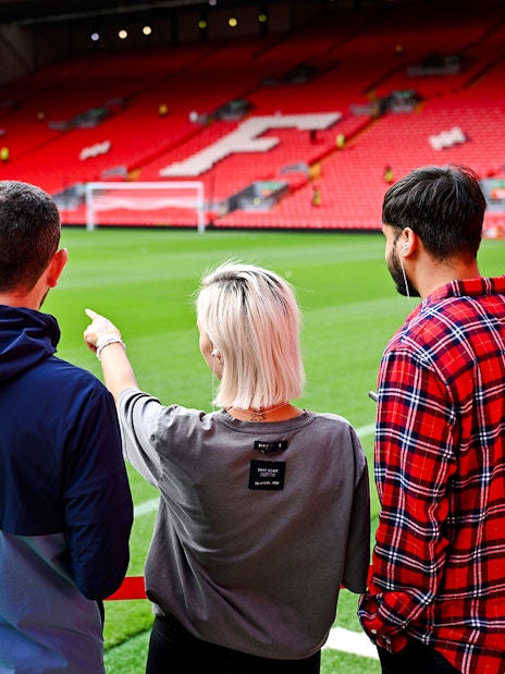 Visitors observing Anfield Stadium field during Liverpool FC tour.