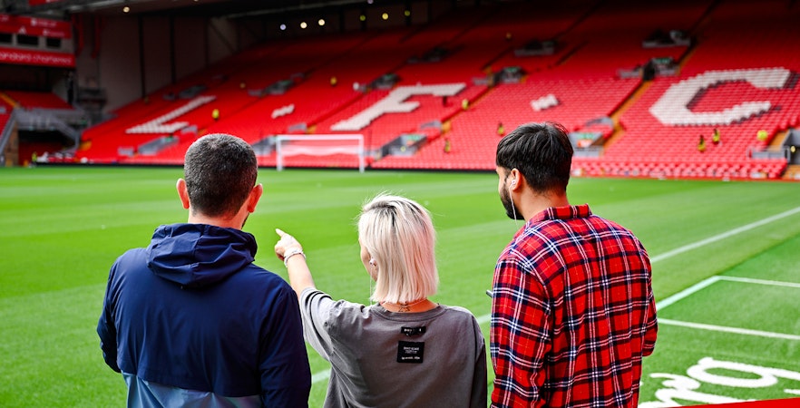 Visitors observing Anfield Stadium field during Liverpool FC tour.