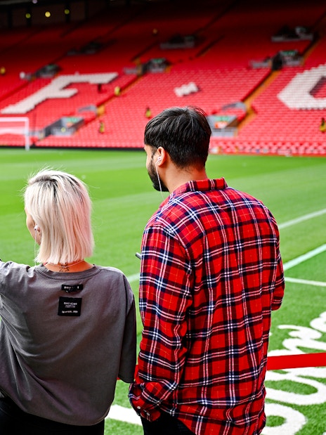 Visitors observing Anfield Stadium field during Liverpool FC tour.