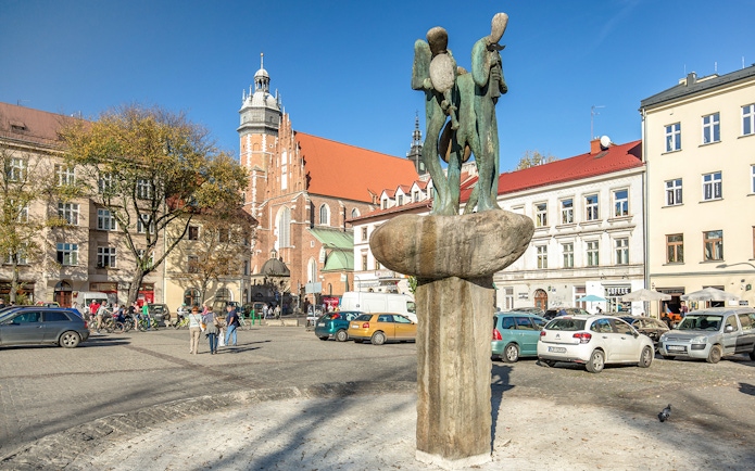 Kazimierz Plac Wolnica statue fountain in Krakow's Jewish Ghetto with historic buildings.