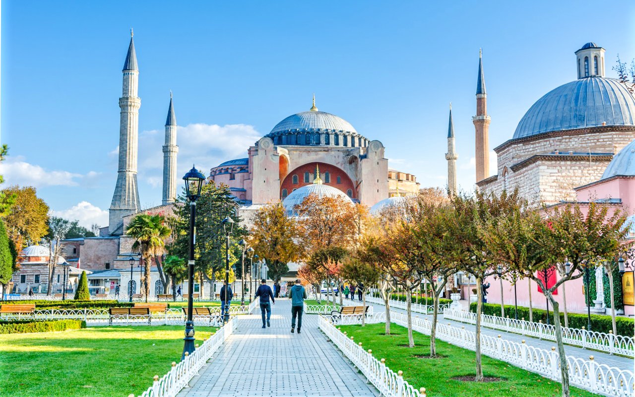 Courtyard view of the Blue Mosque in Istanbul, Turkey, with minarets and trees.
