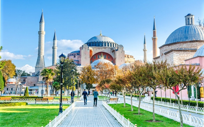 Courtyard view of the Blue Mosque in Istanbul, Turkey, with minarets and trees.