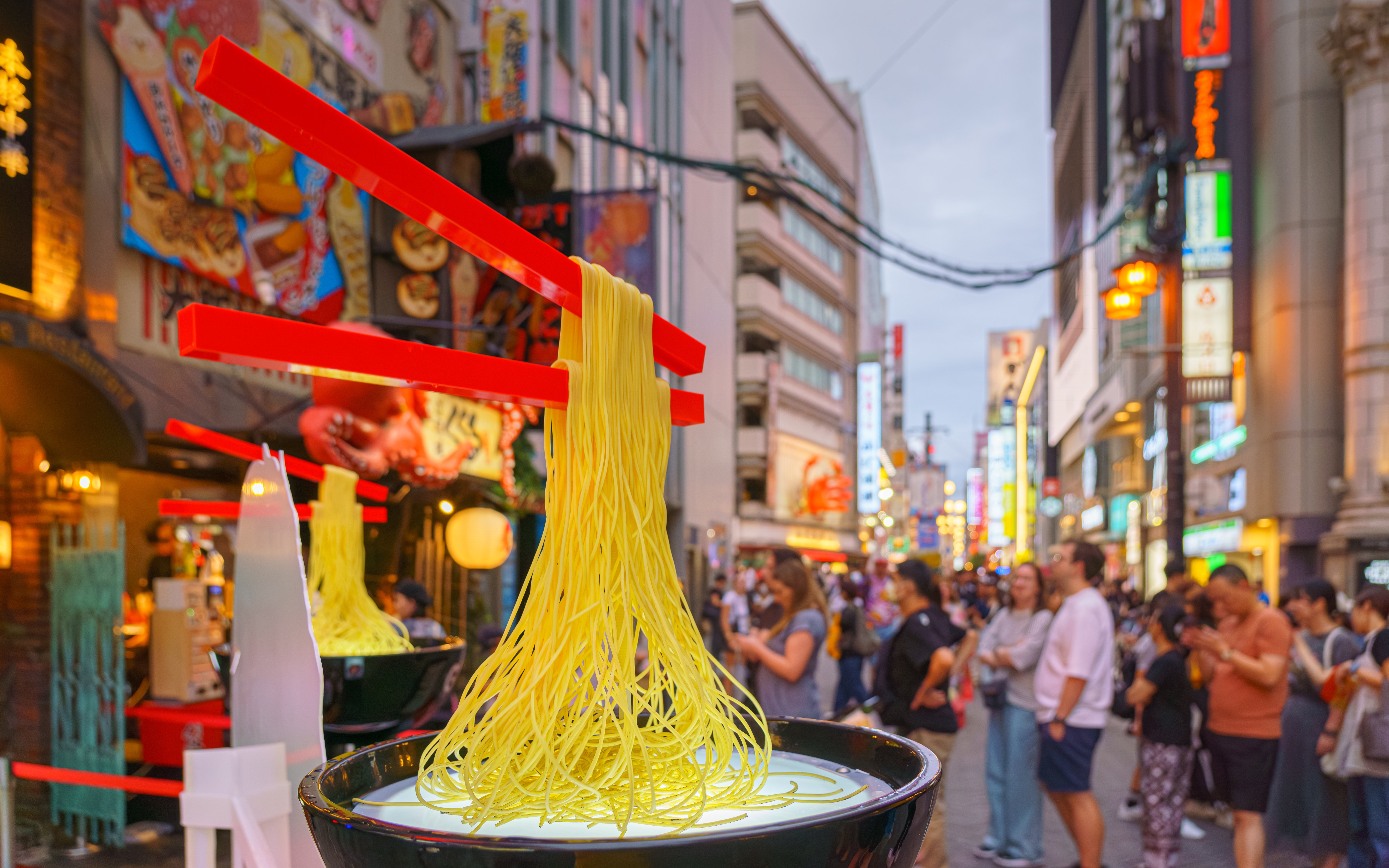 Noodles with floating chopsticks in front of building signs, Osaka, Japan.