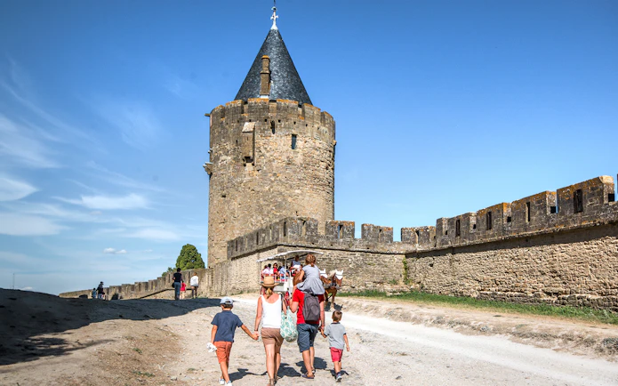 Tourists walking near the walls of Carcassonne Castle, France.