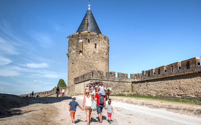 Tourists walking near the walls of Carcassonne Castle, France.