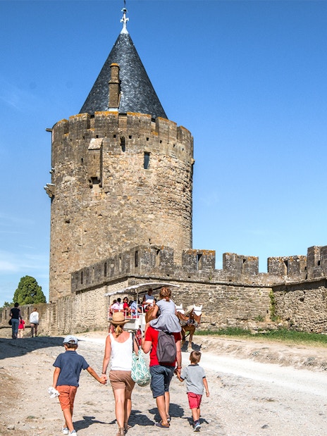 Tourists walking near the walls of Carcassonne Castle, France.