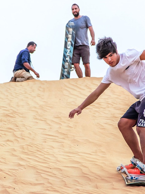 Sandboarding during sunrise desert safari with picnic breakfast.