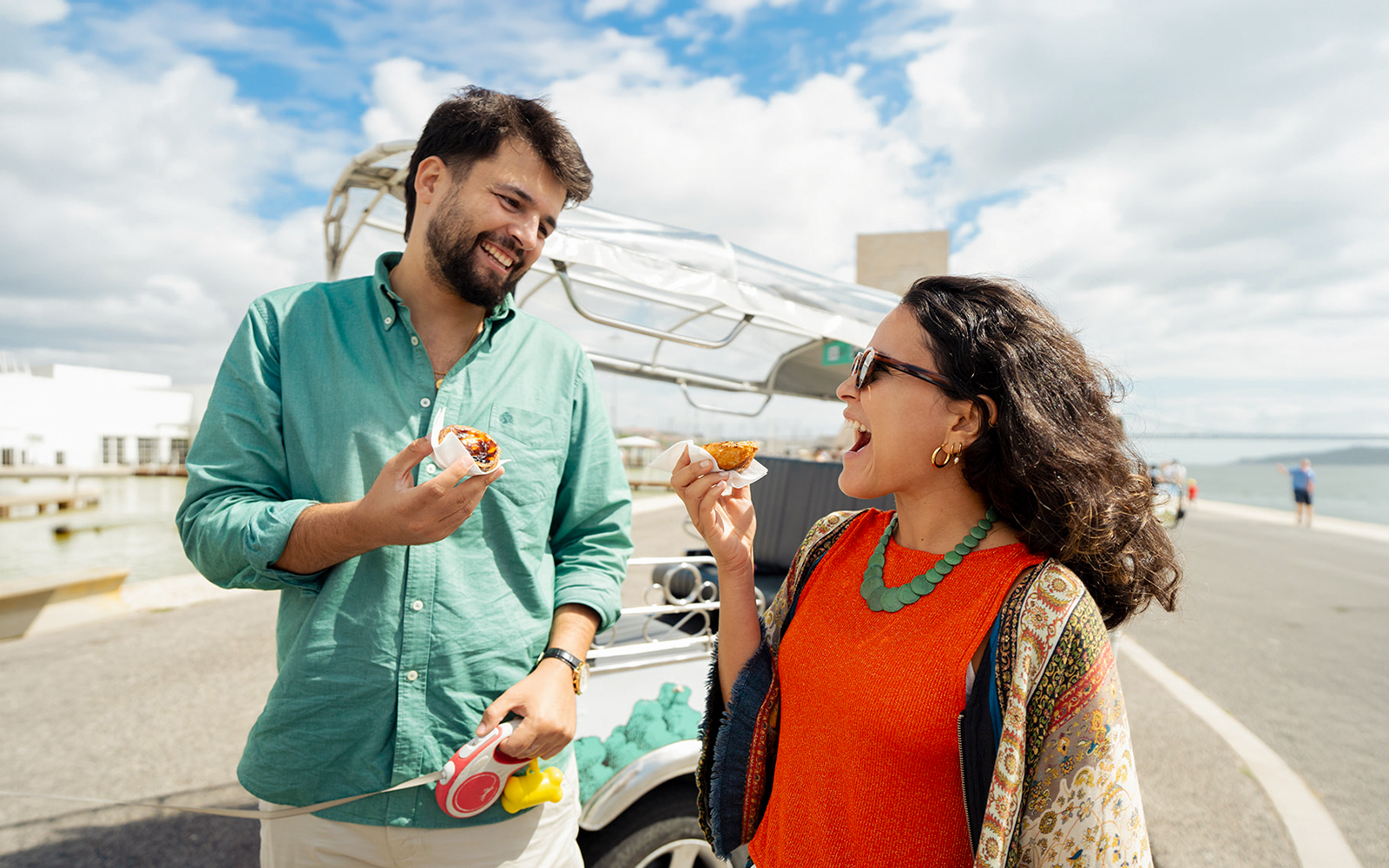 Tourists enjoying snacks during an eco tuk tuk tour in Lisbon by the waterfront.