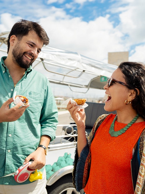 Tourists enjoying snacks during an eco tuk tuk tour in Lisbon by the waterfront.