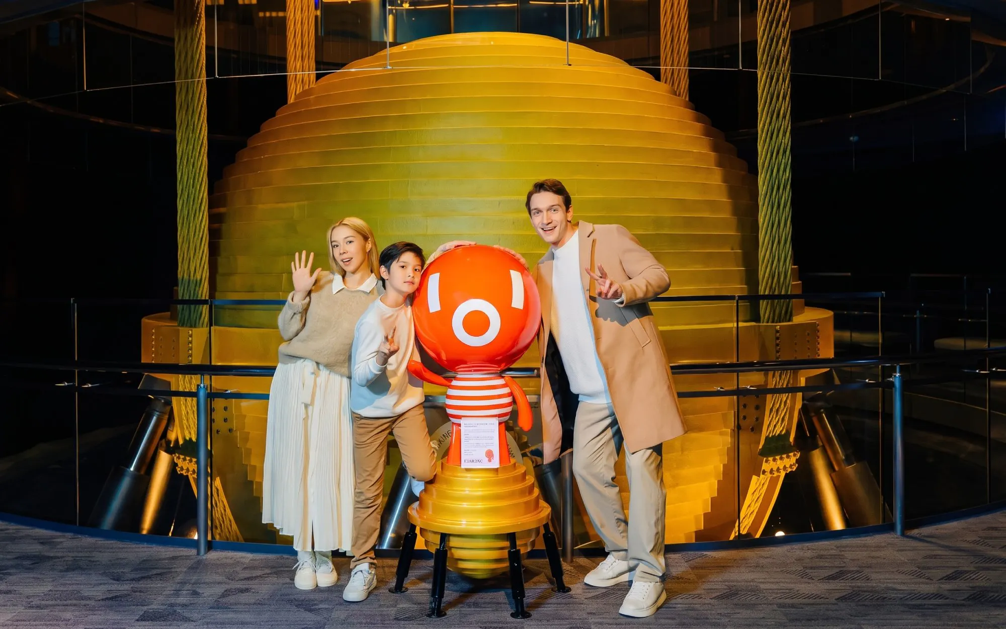 Visitors posing with mascot at Taipei 101 Observatory near the tuned mass damper.