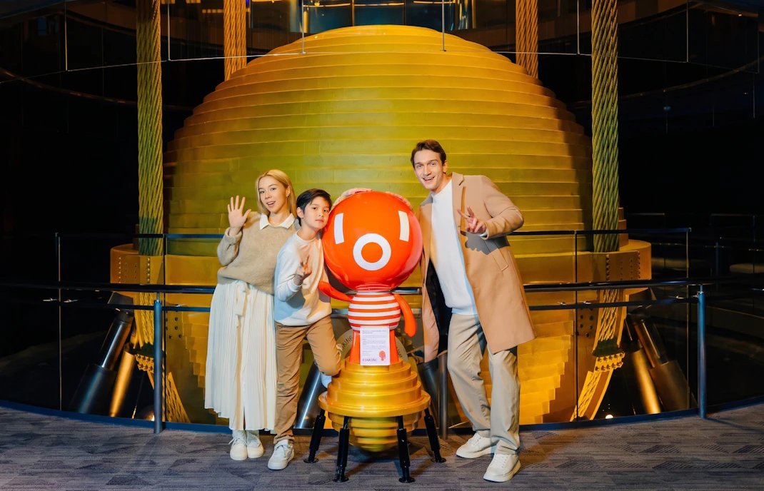 Visitors posing with mascot at Taipei 101 Observatory near the tuned mass damper.
