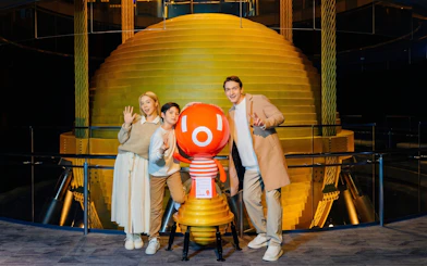 Visitors posing with mascot at Taipei 101 Observatory near the tuned mass damper.