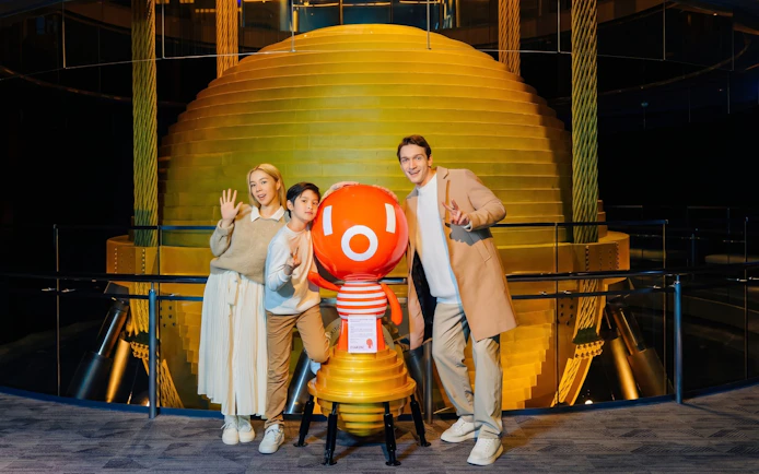 Visitors posing with mascot at Taipei 101 Observatory near the tuned mass damper.