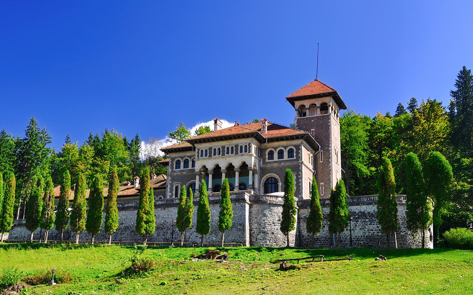 Cantacuzio Castle in Busteni, Romania, surrounded by lush greenery and tall trees.
