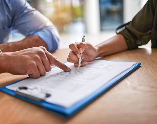 Signing a contract agreement with a pen on a clipboard.