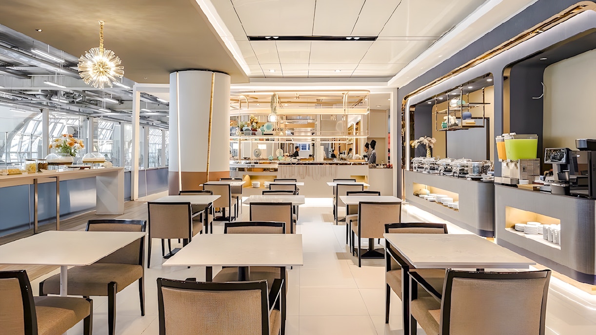 Dining area in Miracle Lounge at Bangkok Airport, featuring tables, chairs, and a buffet setup.
