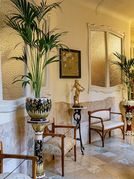 La Pedrera Casa Mila living room with ornate chairs and decorative plants.