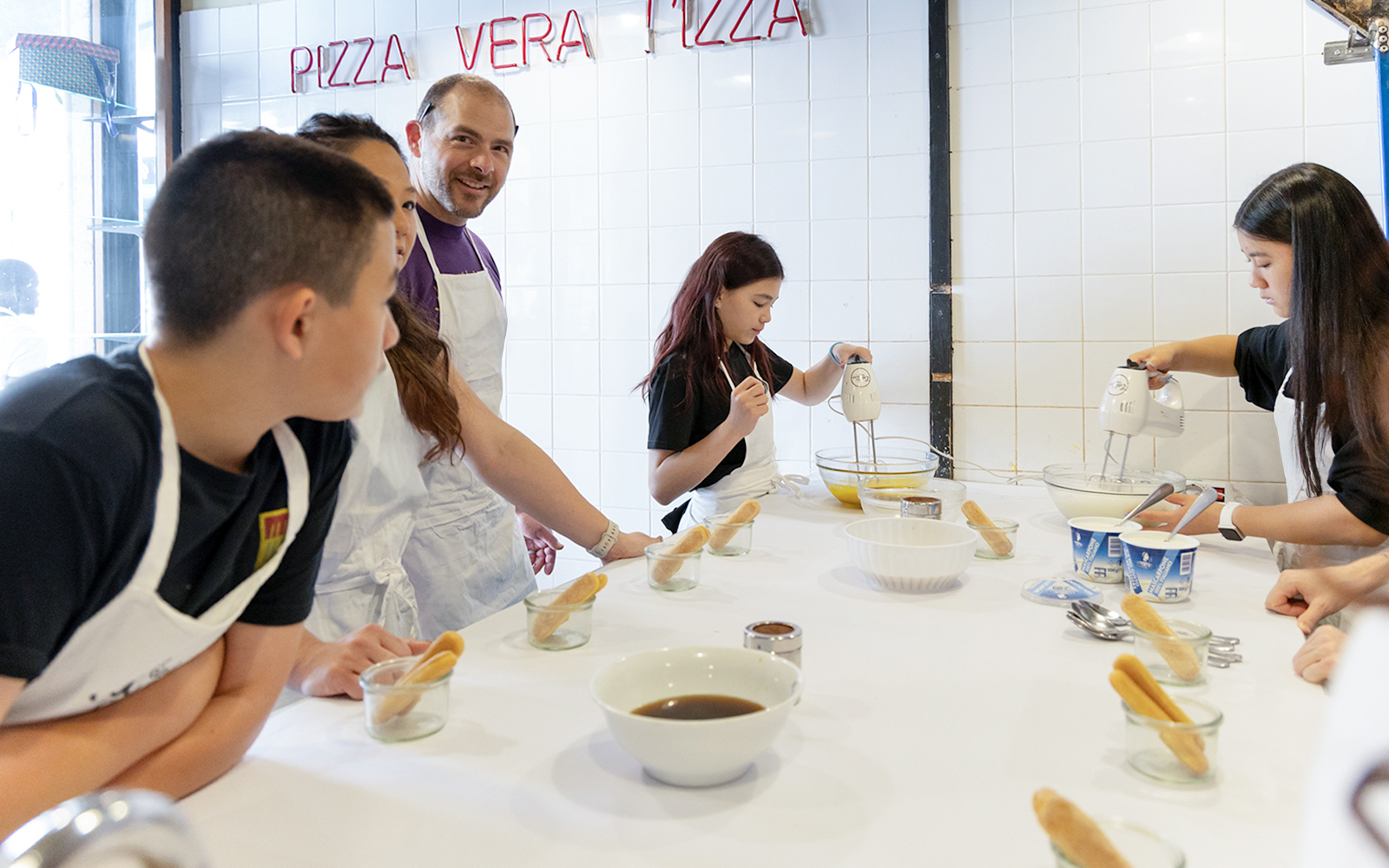 Participants making tiramisu in a Rome cooking class kitchen.