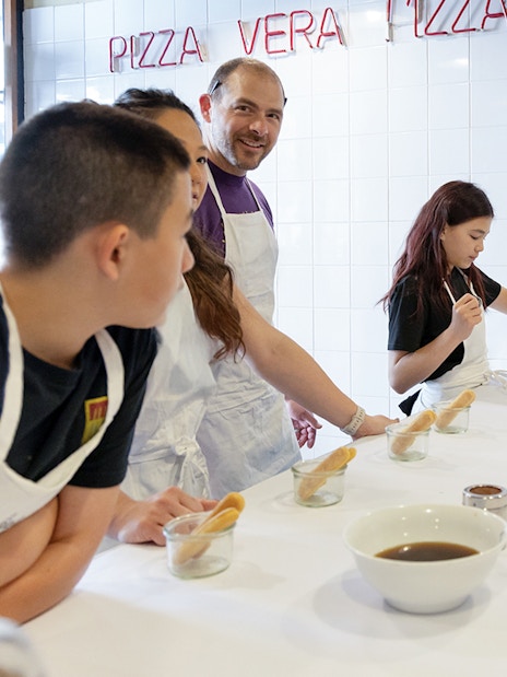 Participants making tiramisu in a Rome cooking class kitchen.