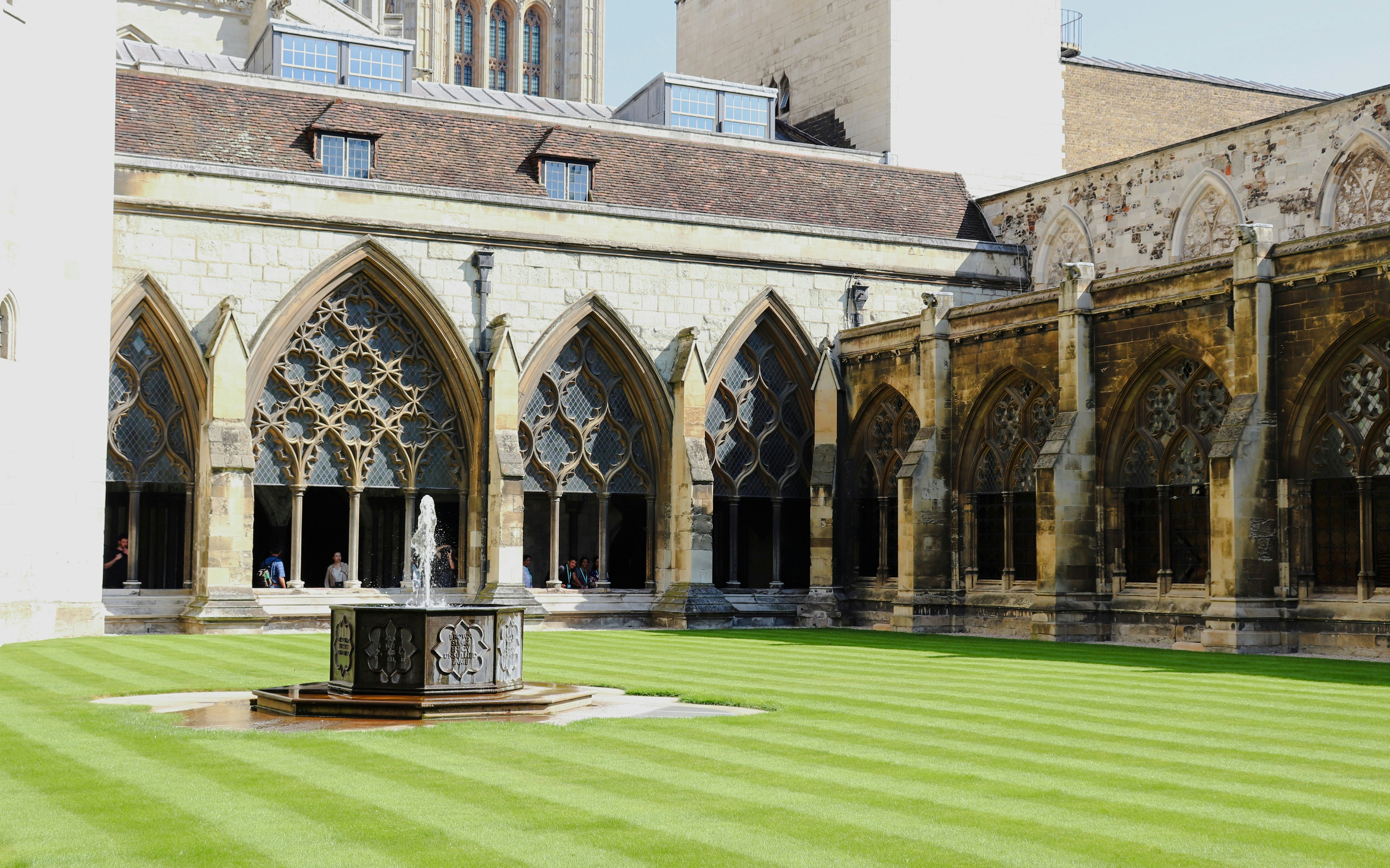 Westminster Abbey cloisters with arched windows and central fountain in London.