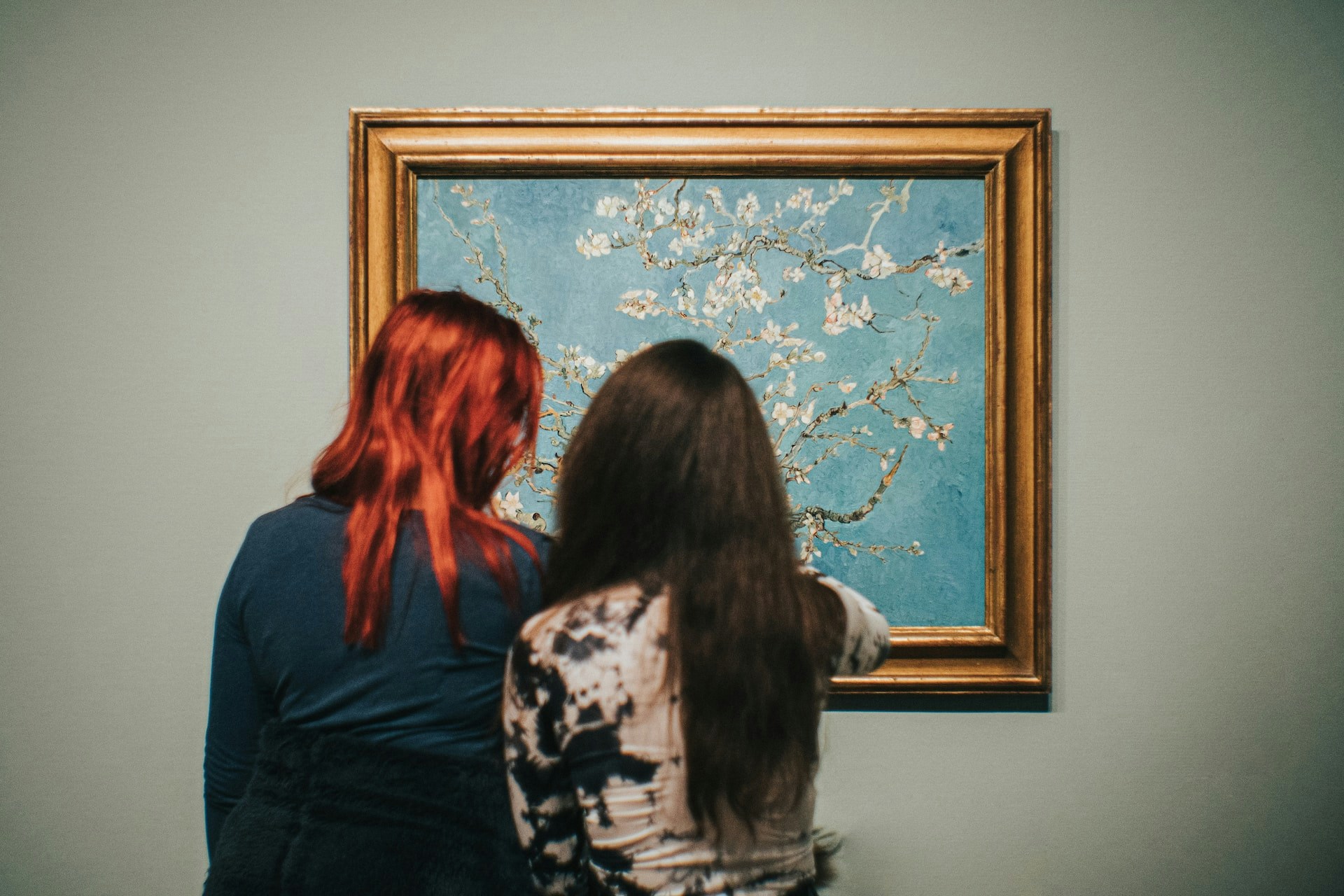 Visitors viewing Van Gogh's "Almond Blossoms" painting in a museum.