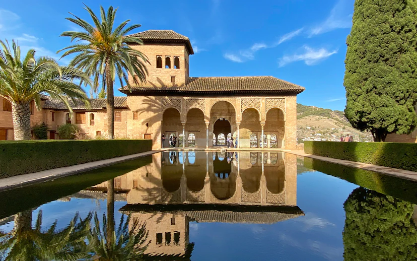Nasrid Palace reflecting pool with arches and palm trees at Alhambra, Granada.