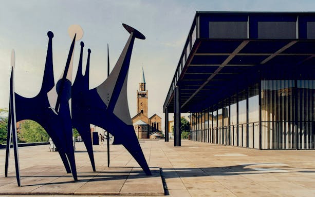 Sculpture outside Neue Nationalgalerie, Berlin, with church in background.