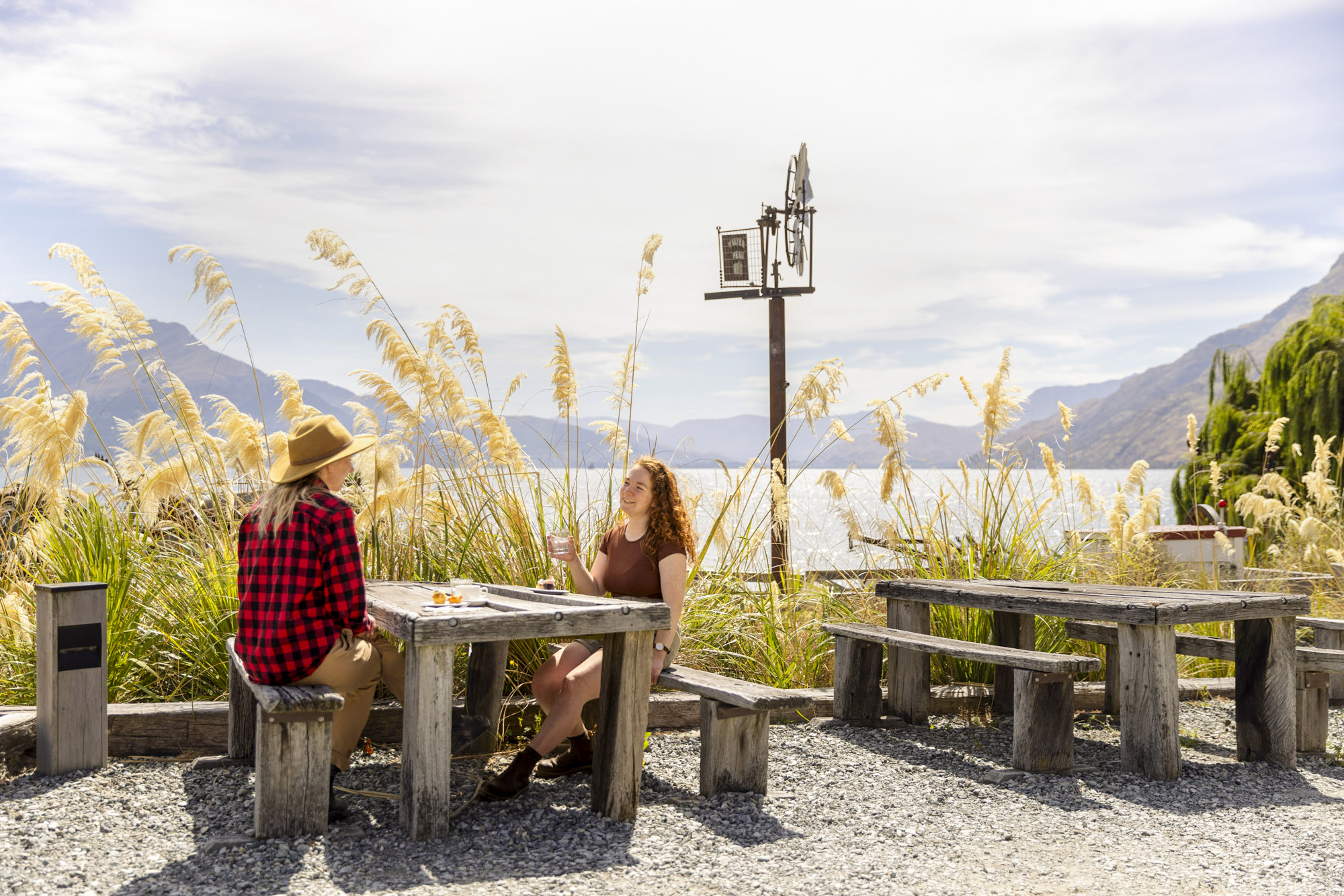 Tourists enjoying a meal at Walter Peak High Country Farm with lake and mountain views.