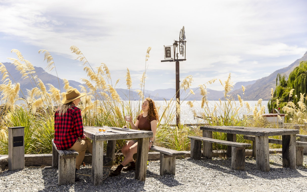 Tourists enjoying a meal at Walter Peak High Country Farm with lake and mountain views.
