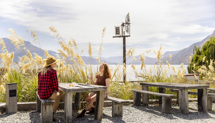 Tourists enjoying a meal at Walter Peak High Country Farm with lake and mountain views.