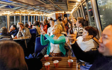 People enjoying the Amsterdam Light Festival cruise, taking photos through the boat's glass roof.