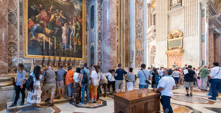 Visitors inside St. Peter's Basilica in Rome viewing artwork and architecture.