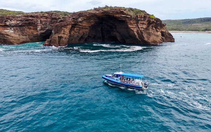 Boat touring near sea cave on Lake Macquarie coast.