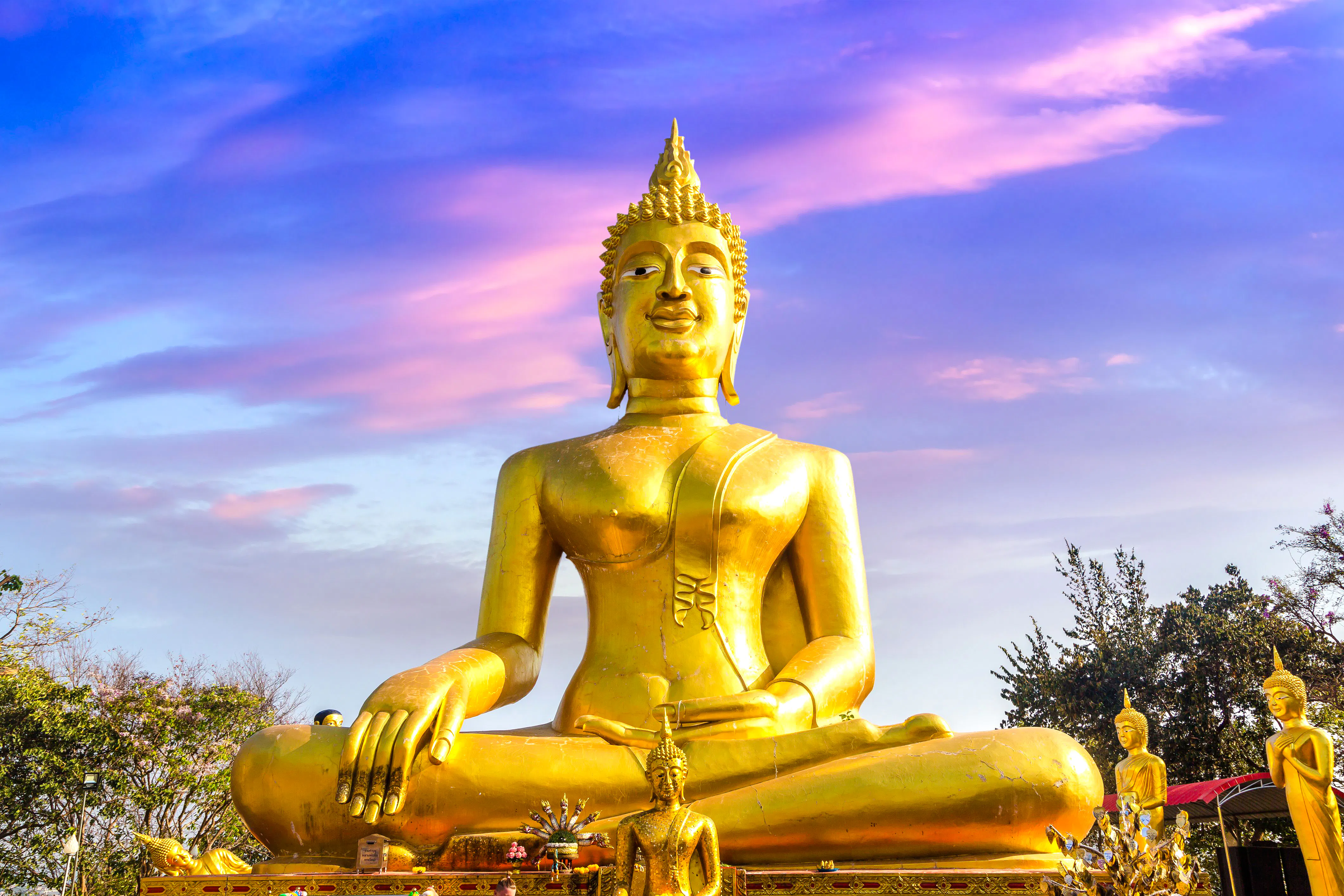 Golden Buddha statue at Wat Phra Yai, Pattaya, under a vibrant sky.
