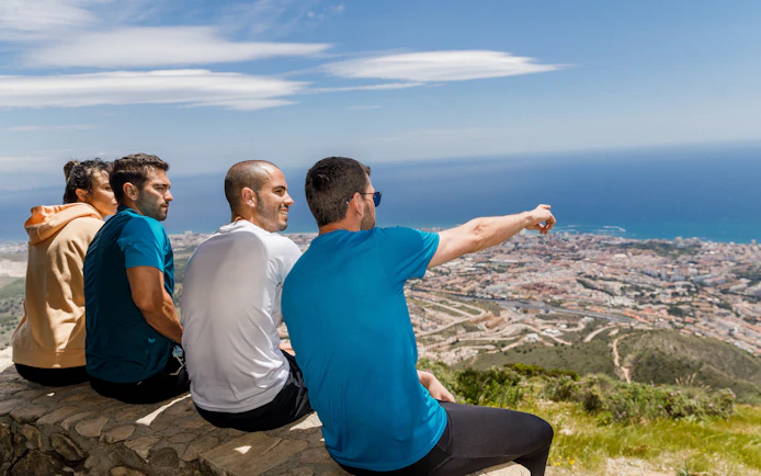 Hikers enjoying the view from Benalmádena mountain summit, overlooking the coastline.