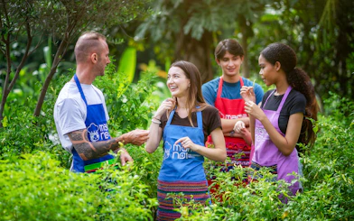 Visitors exploring Mama Noi's organic garden in aprons.