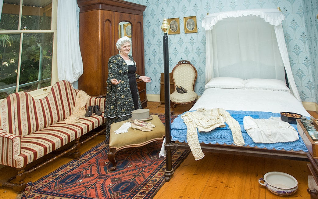 Period-dressed guide in historic bedroom at Churchill Island, Phillip Island Nature Parks.
