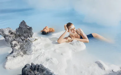 Female tourist relaxing in Blue Lagoon, Iceland, with silica mud on face.